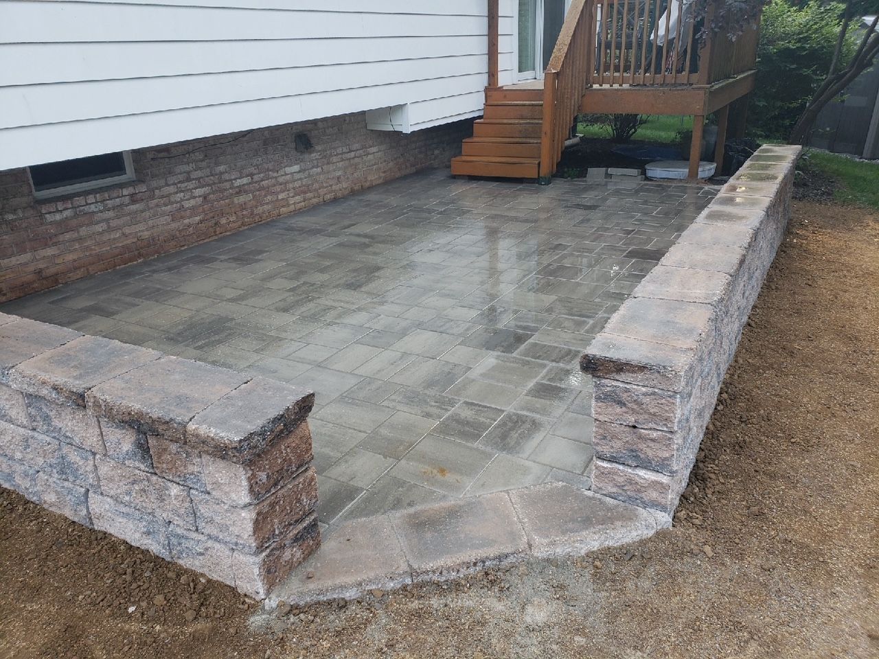 A patio with a brick wall and stairs underneath a house installed by complete property solutions of Lancaster PA