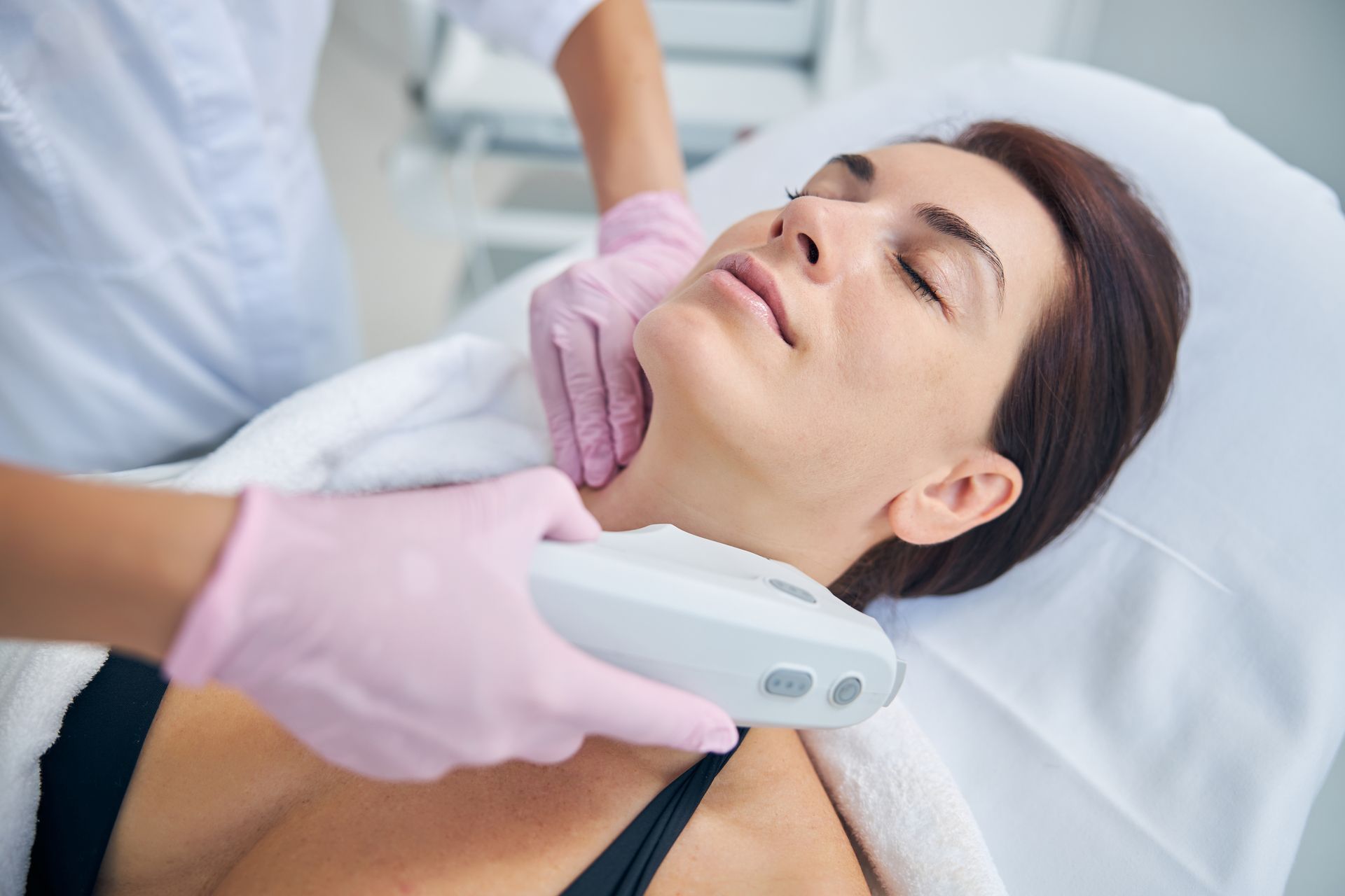 A woman is laying on a bed getting a facial treatment.