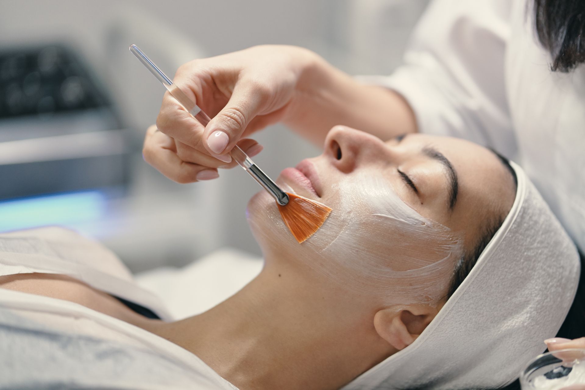 Woman receiving a facial treatment with a brush in a spa setting