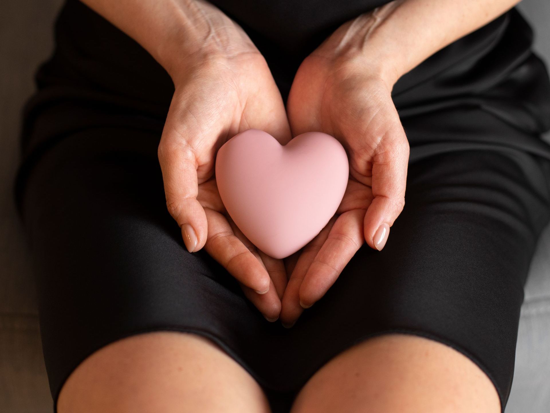 A woman is holding a pink heart in her hands.