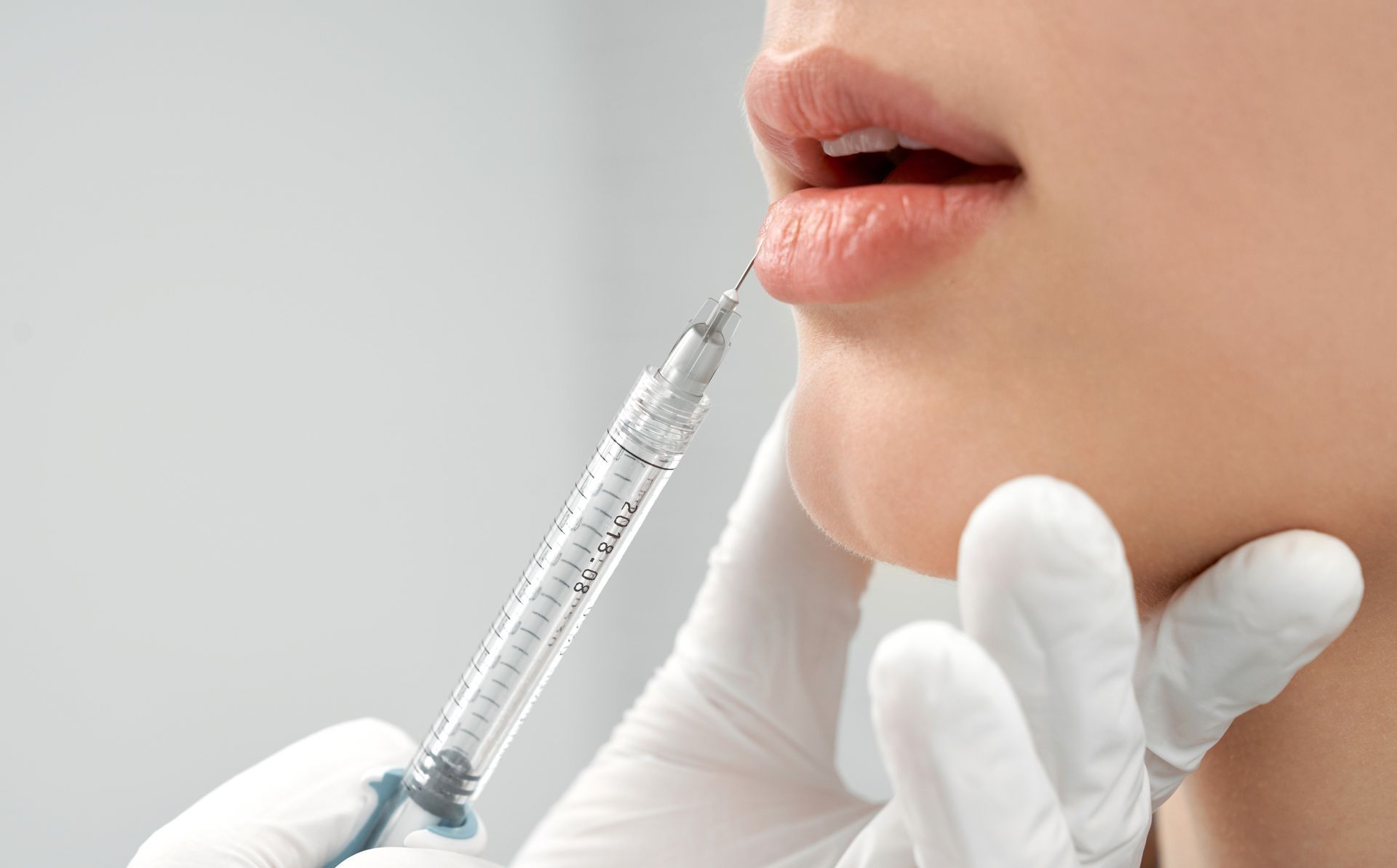 A woman is getting a botox injection in her lips.