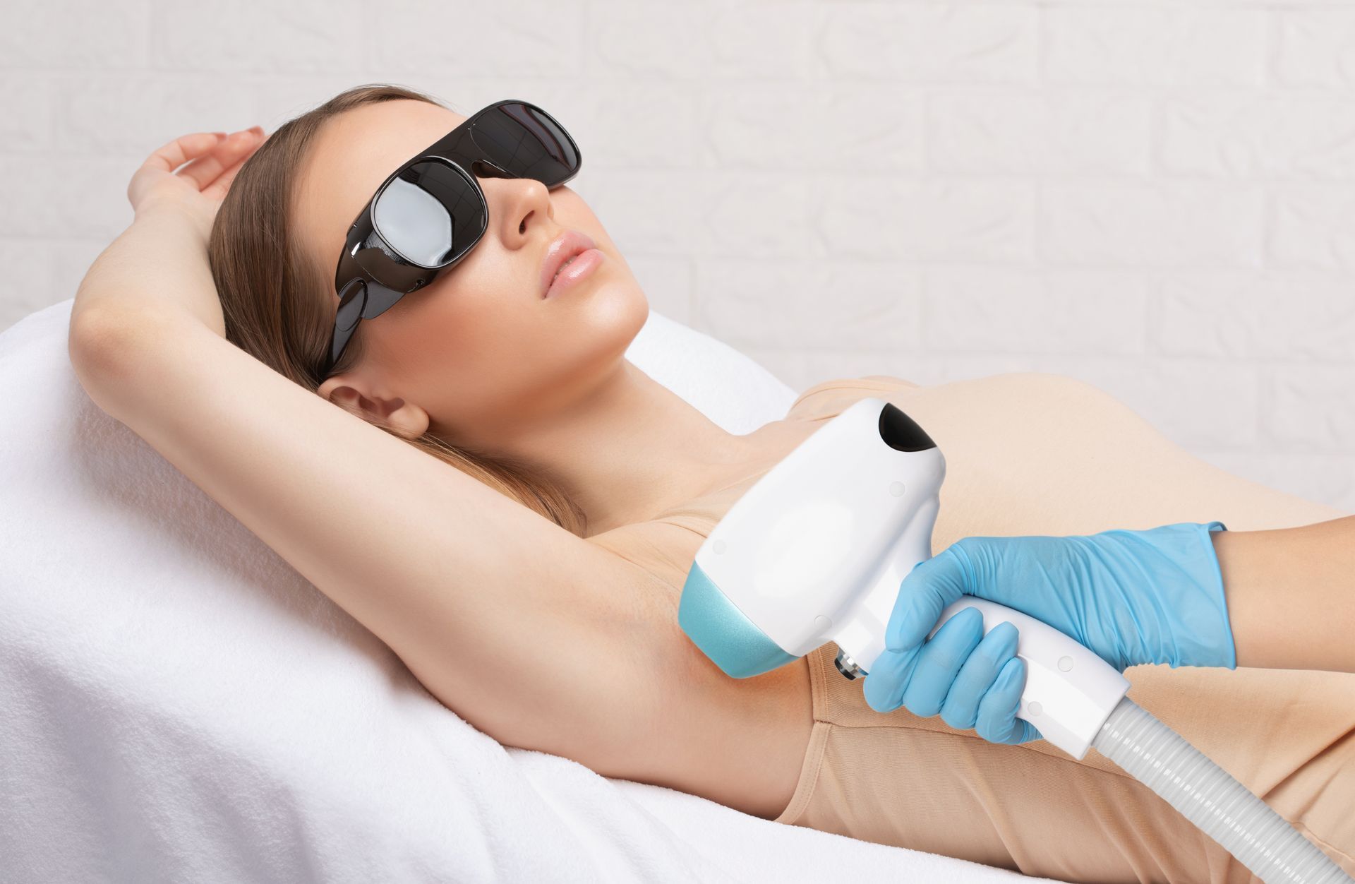 A woman is getting a laser hair removal treatment on her armpit.