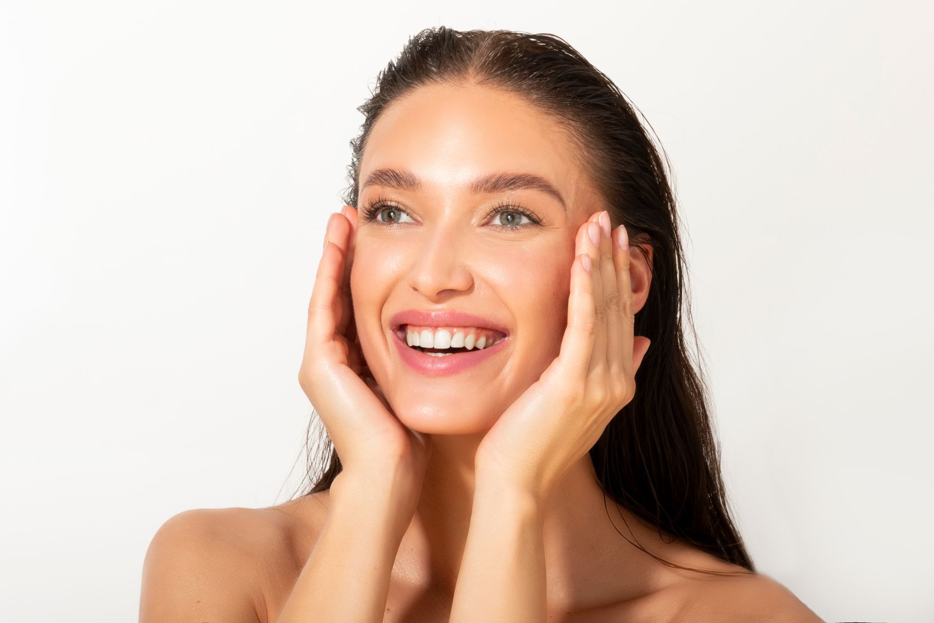 Smiling woman with hands on her cheeks against a white background