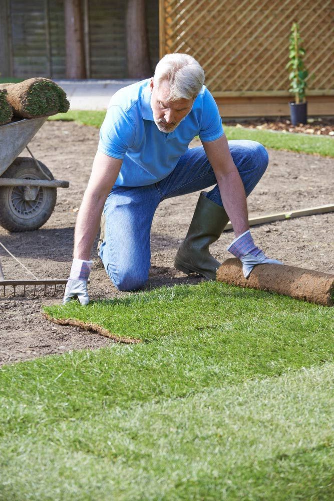 A Man Is Kneeling Down To Roll Out A Roll Of Turf — Barron River Lawns In Biboohra, QLD
