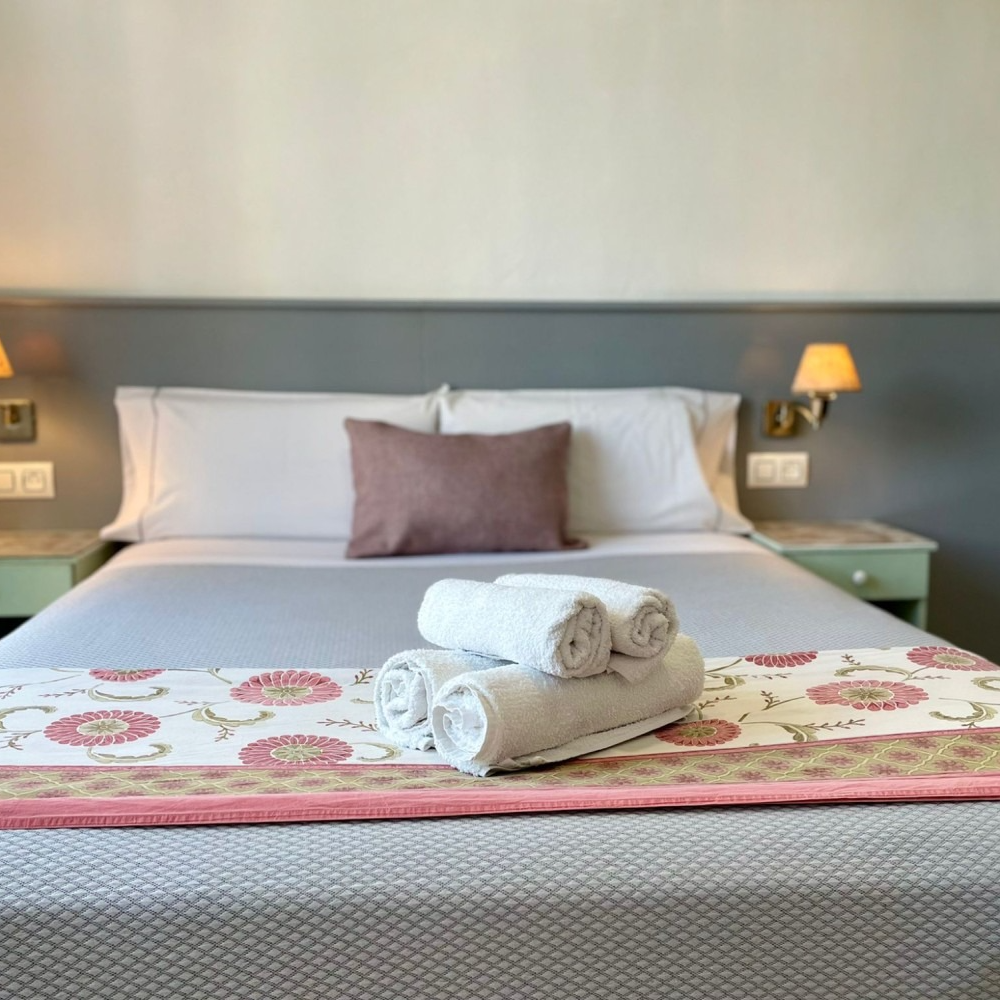 A bed with a pink pillow and towels on it