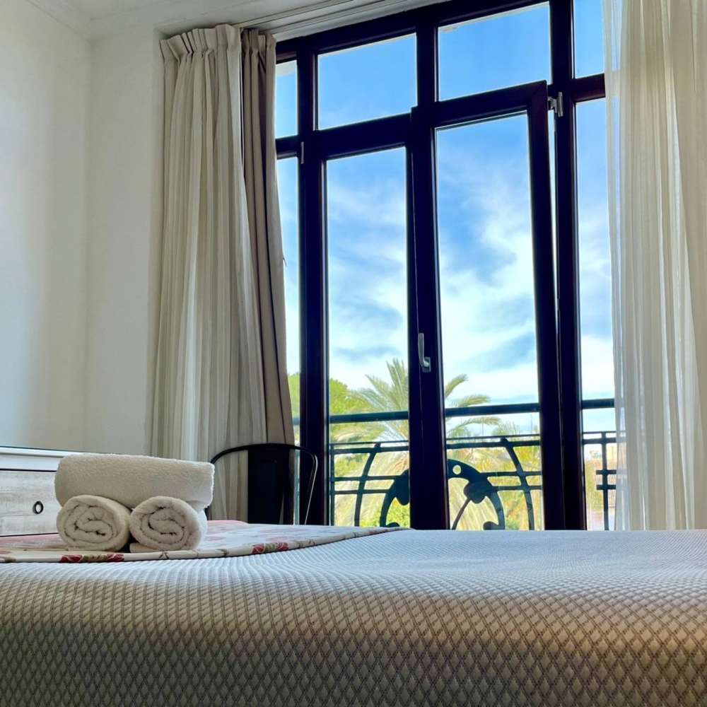 A bedroom with a large window and two towels on the bed