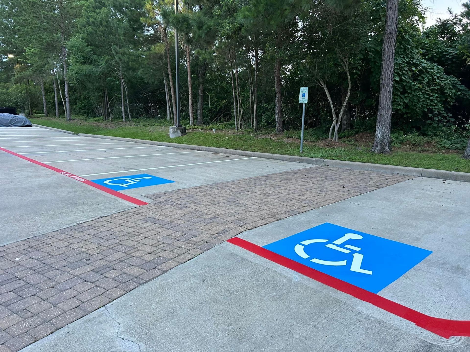 Handicap parking spaces marked in blue with white symbols, red lines on pavement. Brick crosswalk.