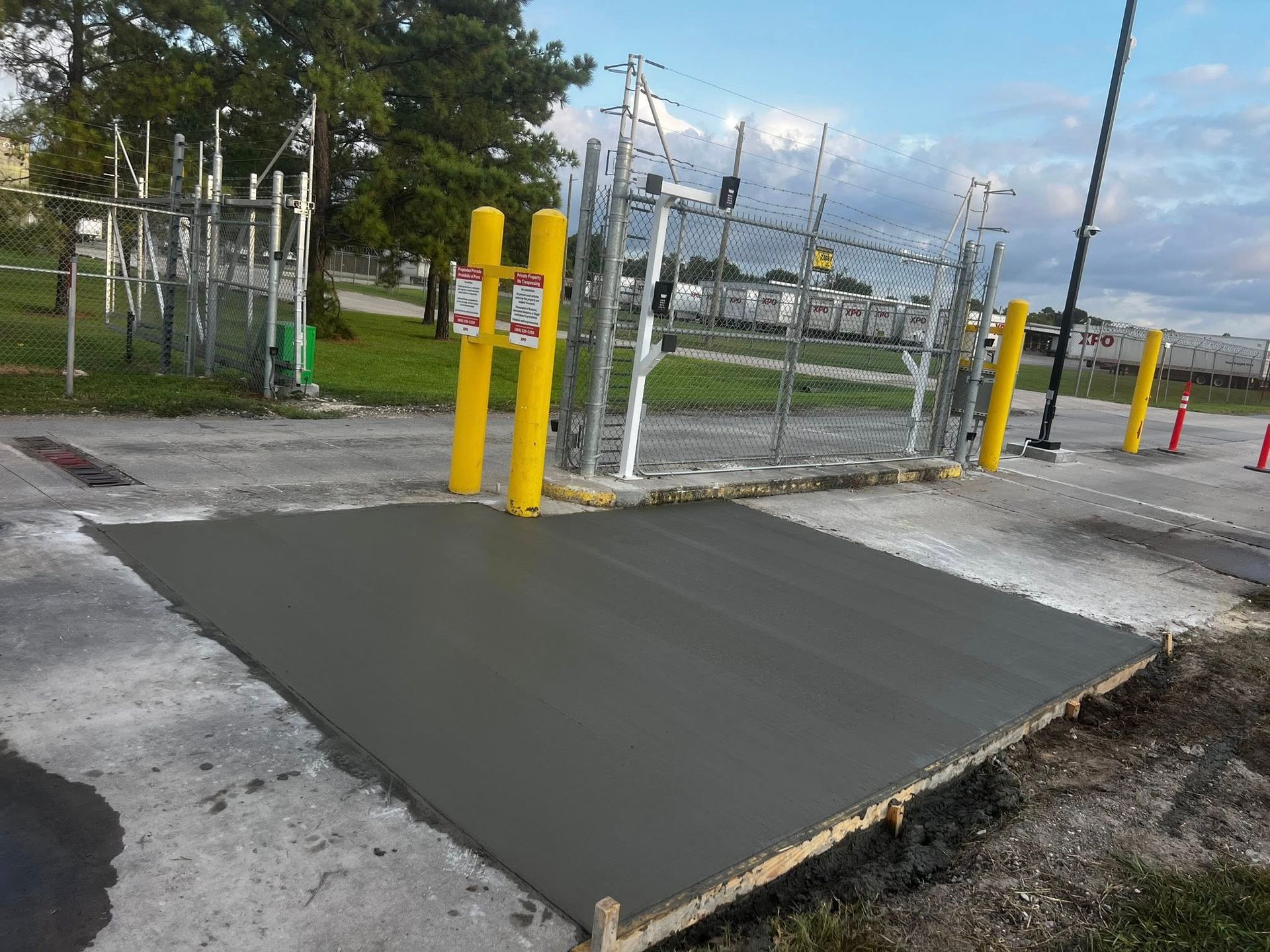 Freshly poured concrete driveway with an orange traffic cone, in front of a house.