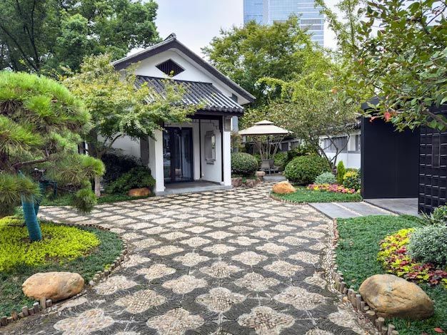 Stone path to a white house with a black door, surrounded by lush green garden and trees