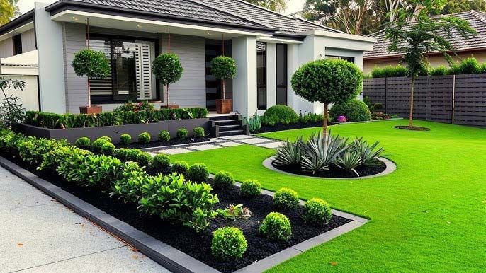 Modern house with manicured lawn, trimmed hedges, and a landscaped front yard with a circular garden bed
