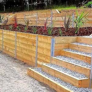 Wooden retaining wall with gravel steps and a raised garden bed of young plants