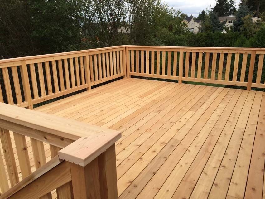 Wooden deck with tan railings overlooking trees and a distant hillside