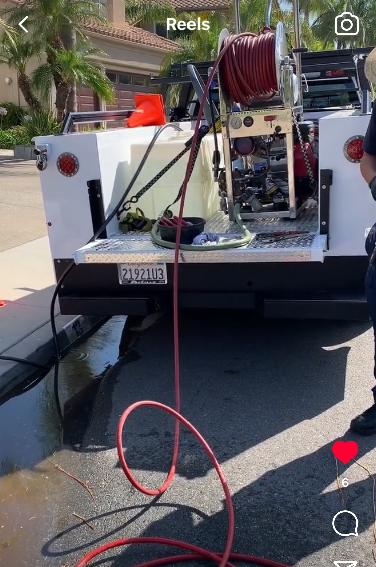 A man is standing next to a truck with a hose attached to it.