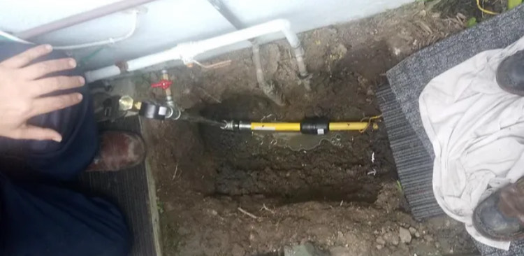 A person is fixing a pipe in the ground.