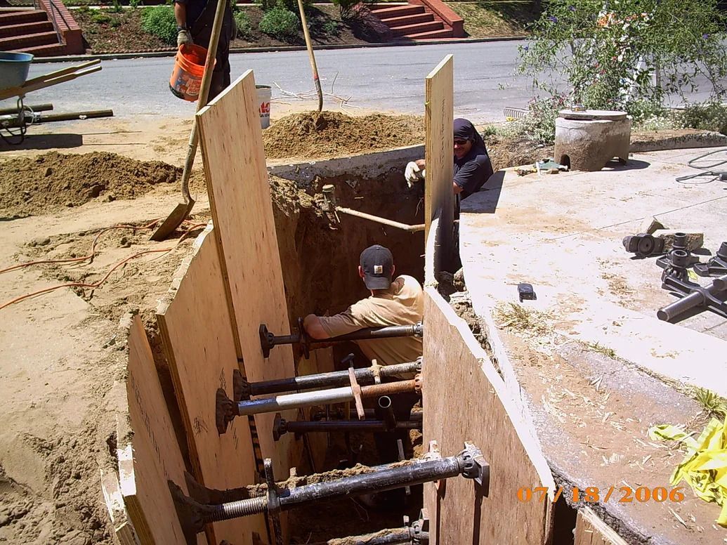 A man is laying in a hole with a wooden wall around him