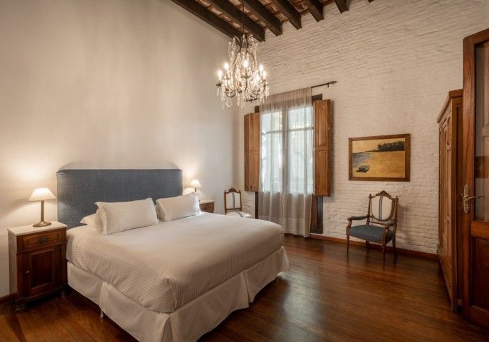 Dormitorio con cama, mesitas de noche, lámpara de araña y suelo de madera.