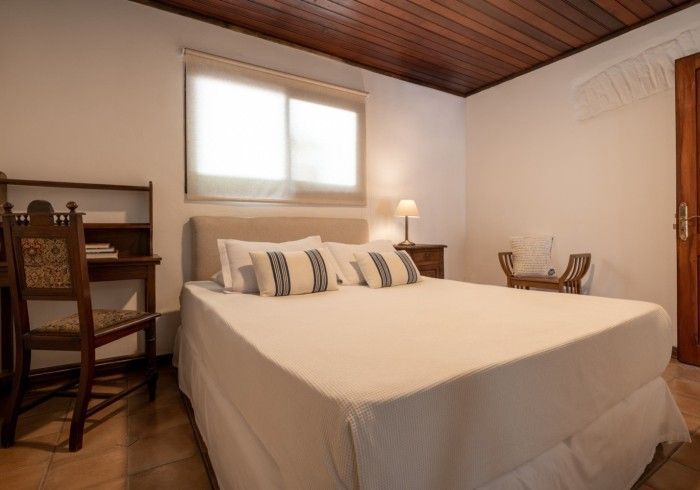 Dormitorio con cama, escritorio y ventana con techo de madera.