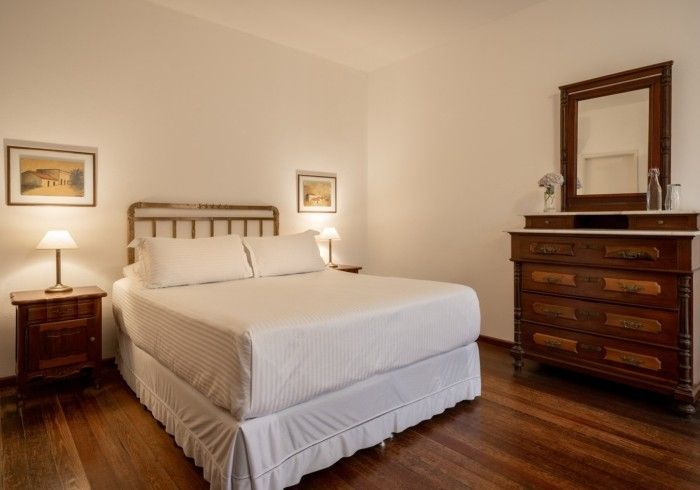 Dormitorio con cama, mesitas de noche, tocador con espejo y suelos de madera.
