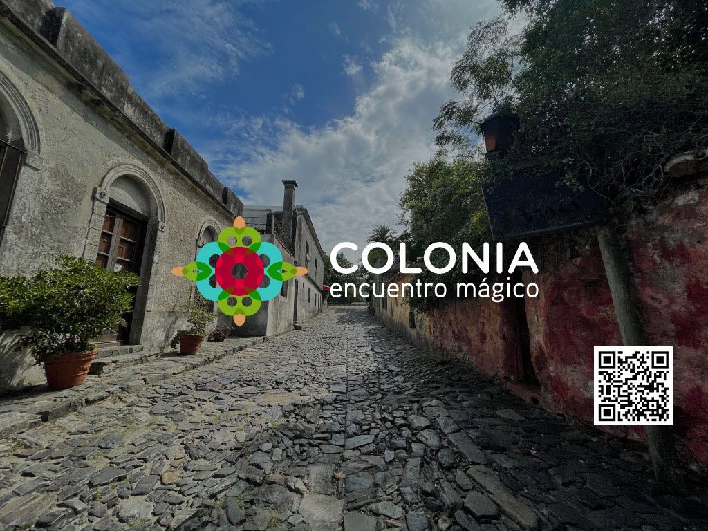 Cobblestone street in Colonia, Uruguay, with old buildings and logo