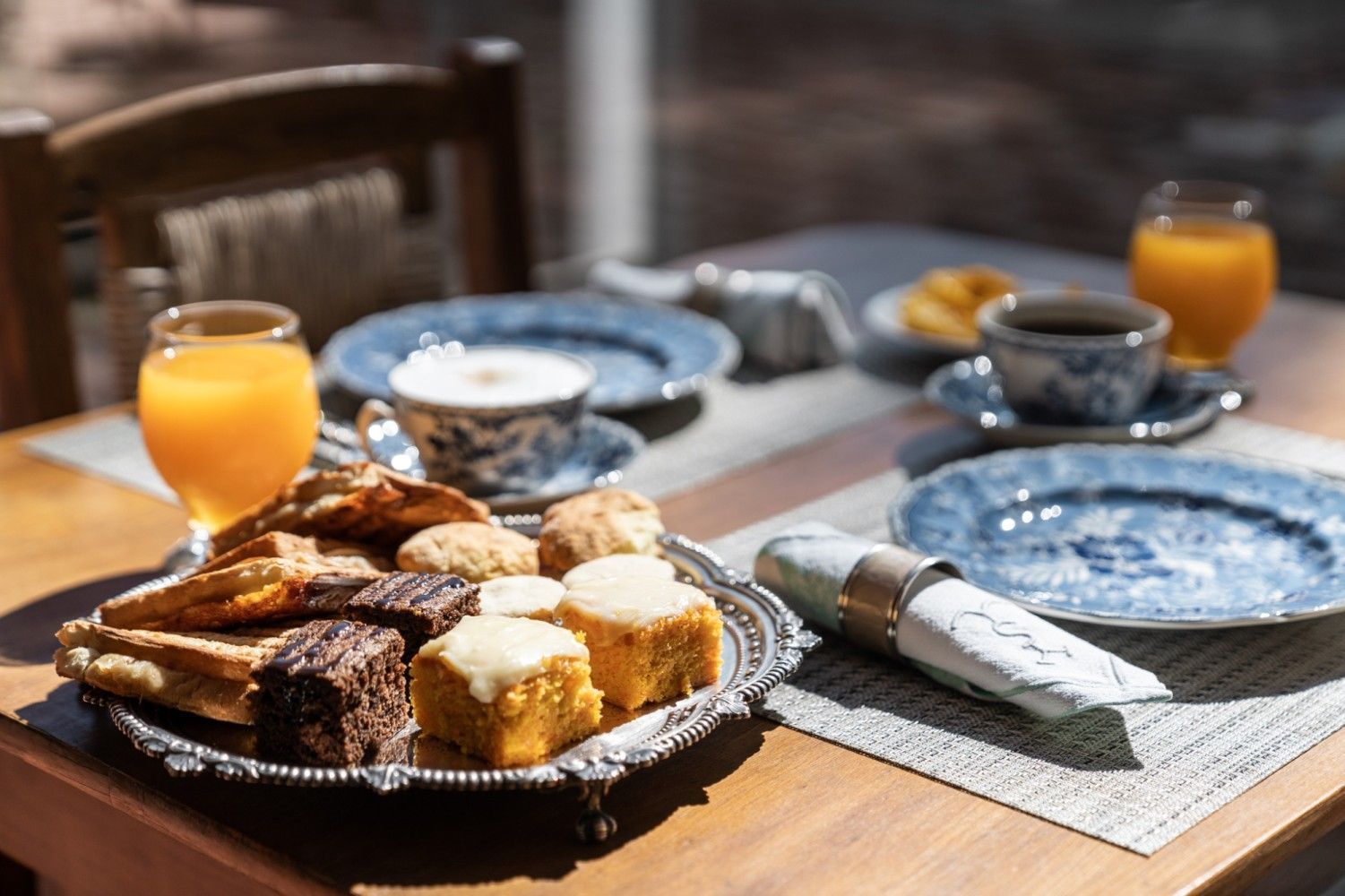 Mesa de desayuno con pasteles, café, jugo y porcelana estampada en color azul.