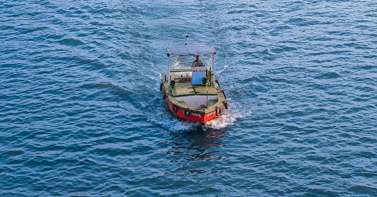 Pequeño barco naranja en el agua azul, dejando una estela.