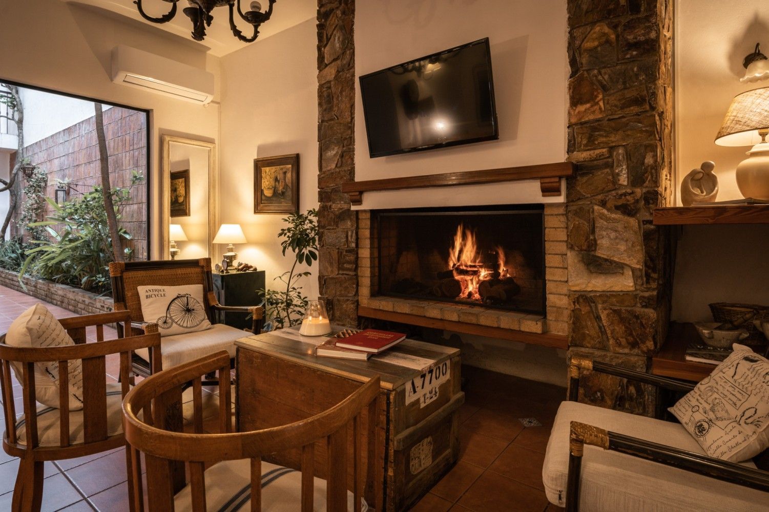 Acogedora sala de estar con chimenea, TV, asientos y vista al aire libre.