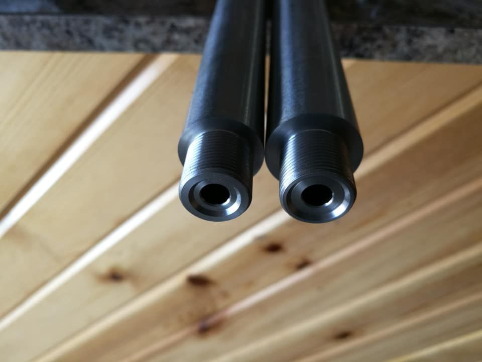 Two black metal tubes mounted under a wooden ceiling, viewed from below