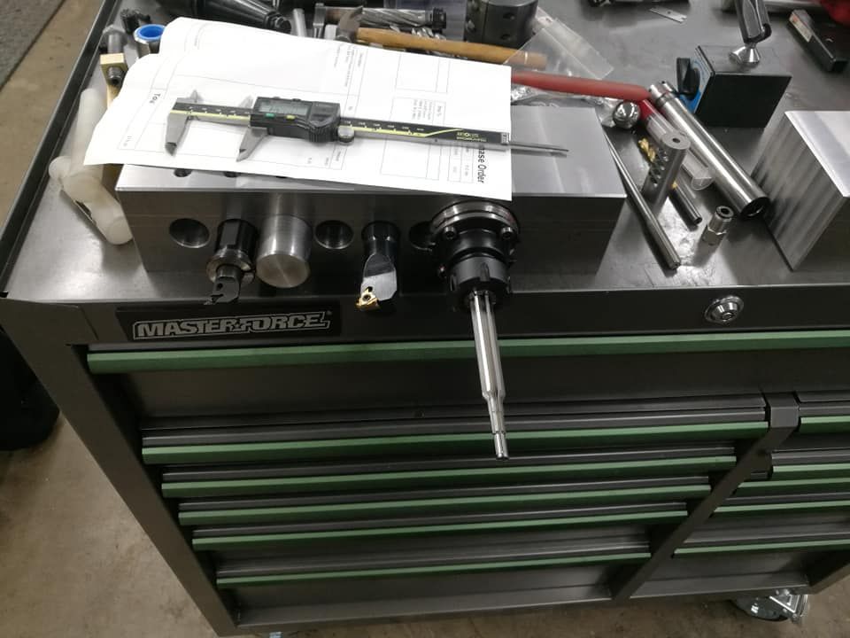 Industrial lathe on a green tool cabinet with tools and a white sheet on top