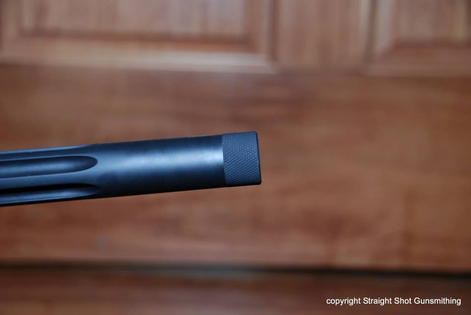 Close-up of a black rifle barrel against a wooden background