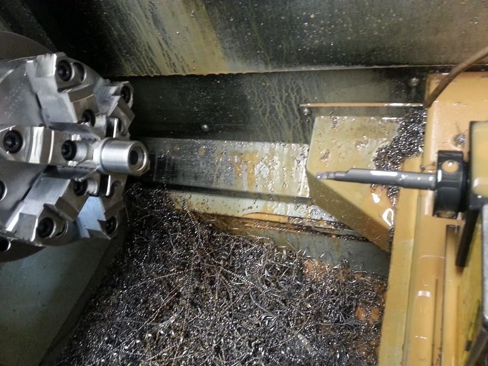CNC lathe cutting metal, with chips collecting in the machine bed