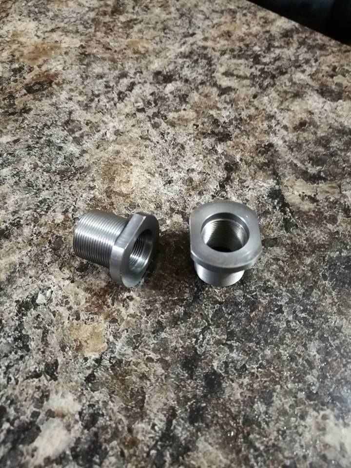 Two small silver metal fittings on a speckled countertop.