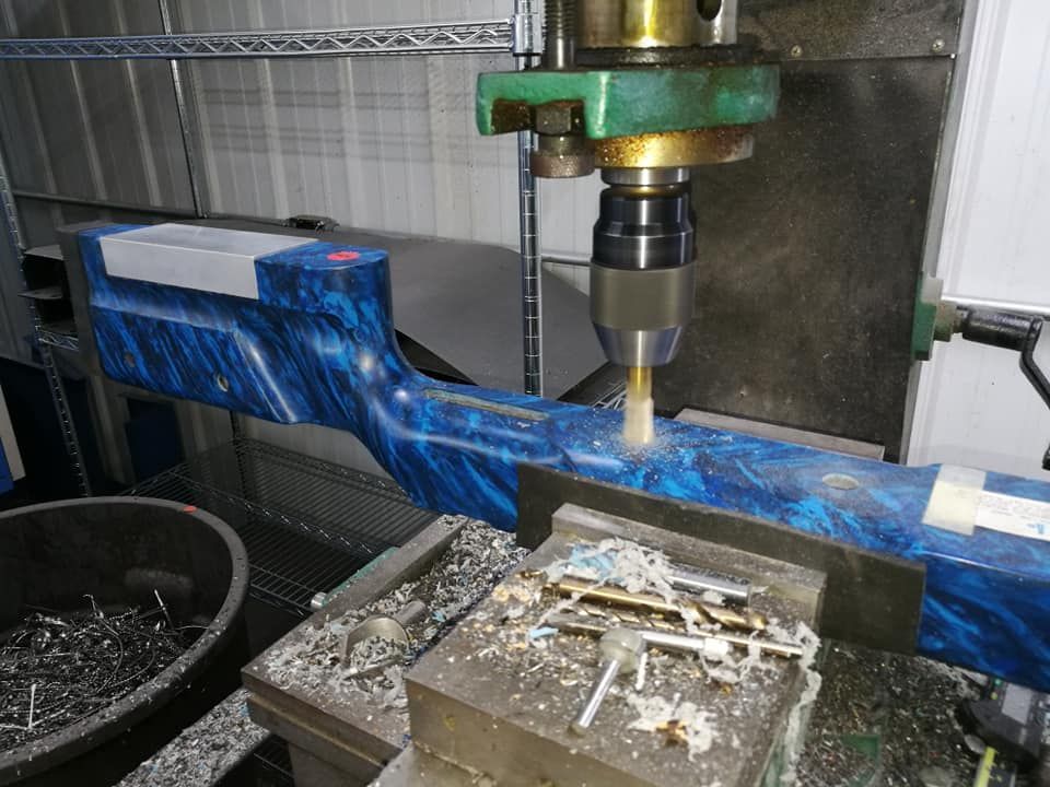 CNC machine cutting a blue metal beam, with metal shavings on the worktable