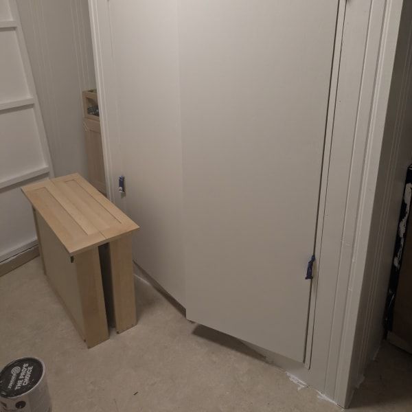 Small wooden bench beside a white closet door in a narrow hallway