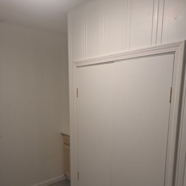 White hallway with a large closet door and built-in cabinetry.