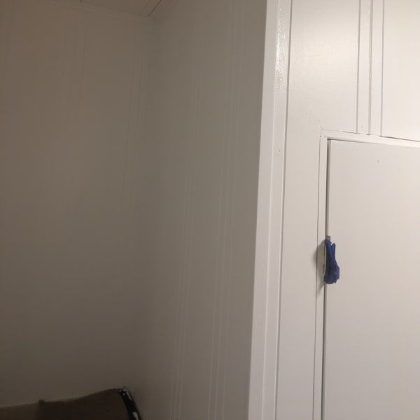 Interior corner with white paneled doors and a gray wall, with a small blue item hanging on the right door.
