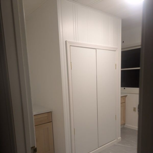 Narrow hallway with white paneled closet doors and built-in cabinets in a bright home interior