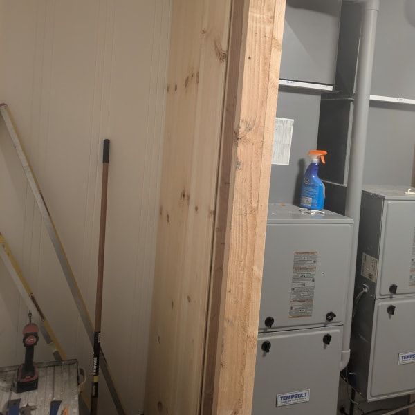 Laundry/utility room with stacked appliances, a wooden support beam, and cleaning supplies on top.