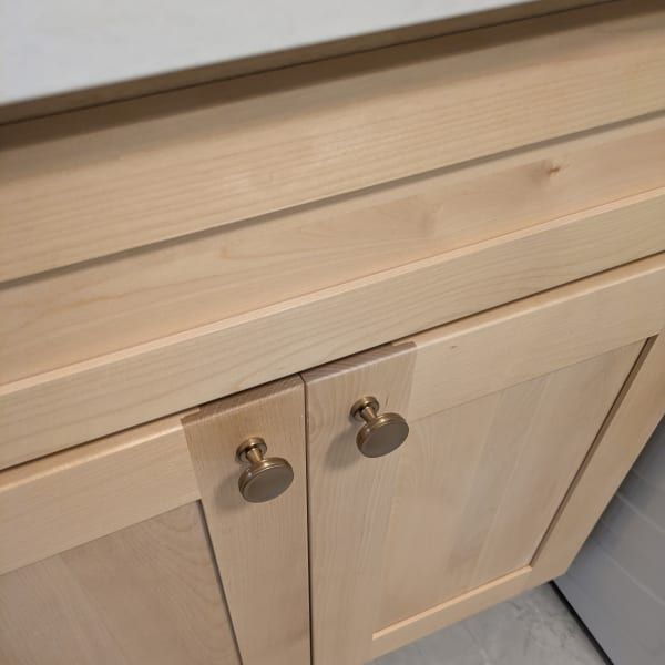 Light wood cabinet doors with round metal knobs beneath a matching countertop.
