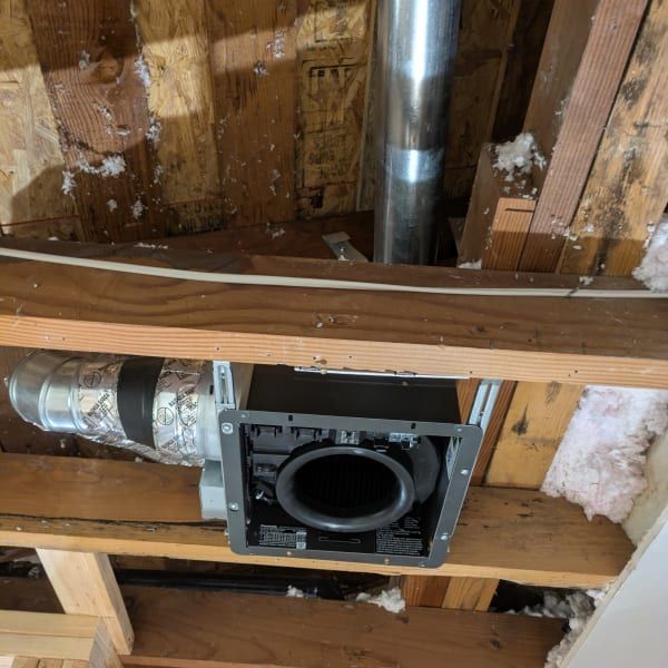 HVAC duct opening in exposed ceiling framing with metal vent pipe and wood beams