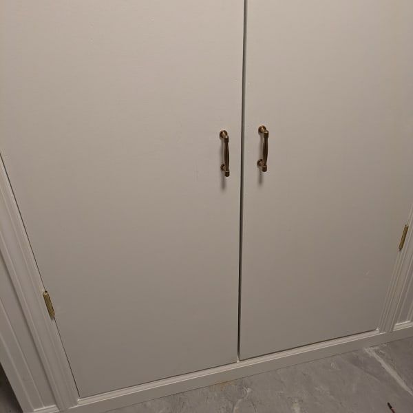 White double closet doors with brass handles in a beige room, viewed from a low angle