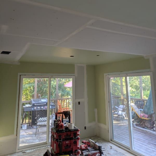 Unfinished room with green walls, white ceiling panels, and large sliding doors opening to a deck.
