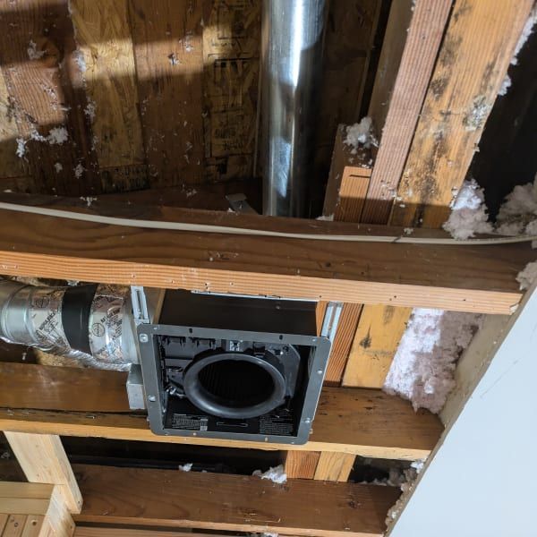 Exposed attic ceiling framing with a square HVAC vent opening and ductwork pipe.