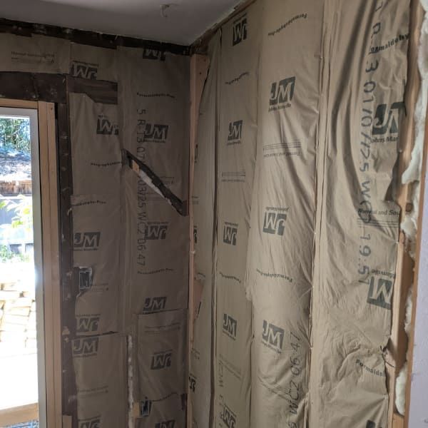 Partially insulated room with exposed framing and a window letting in daylight