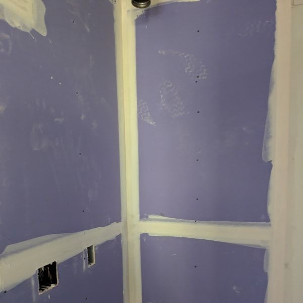 Purple drywall room with white joint tape and unfinished electrical outlets