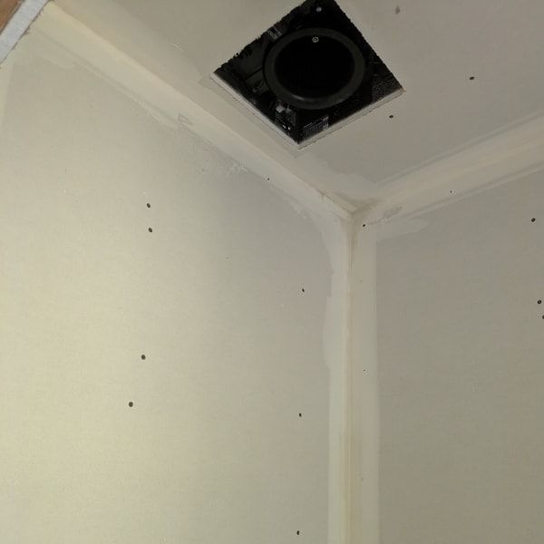 White interior ceiling corner with a square vent opening and visible screw holes in the wall.