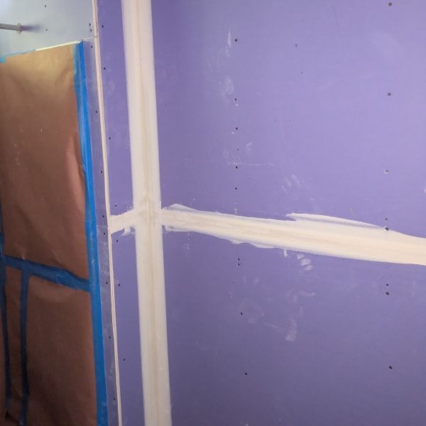 Purple wall with white taped seams and a partially covered door frame on the left