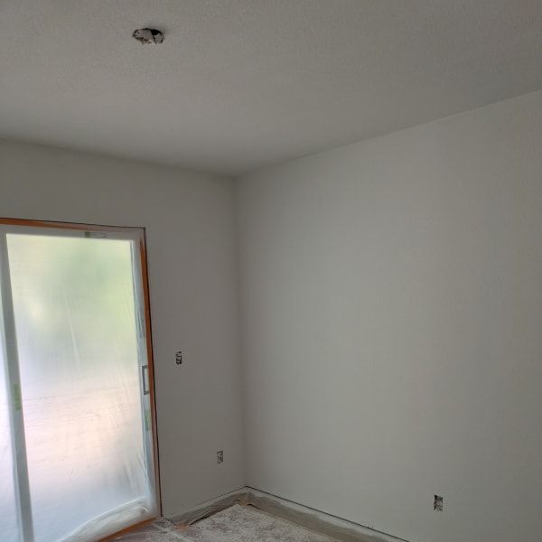 Empty white room with unfinished floor and a frosted glass door.