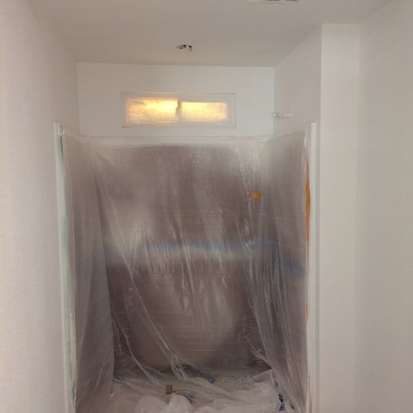 Bathroom under renovation, with a shower/tub covered in clear plastic sheeting.
