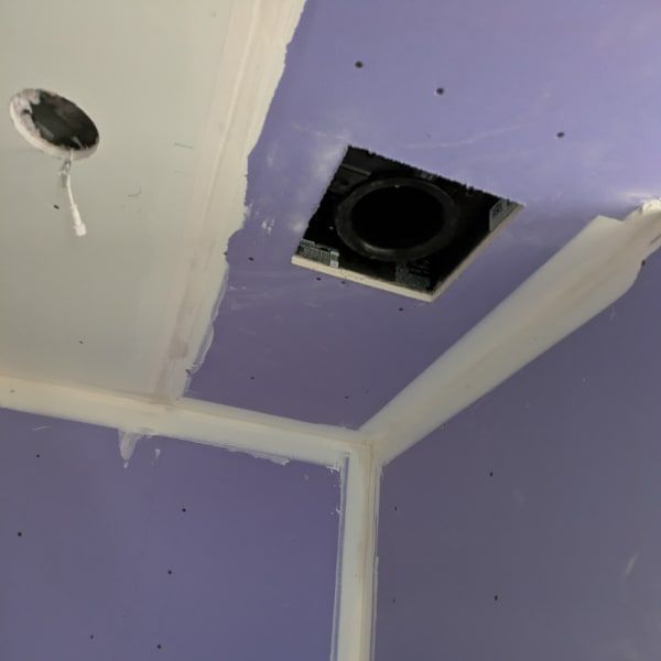 Purple drywall ceiling corner with white joint tape and two cutouts for vents or fixtures