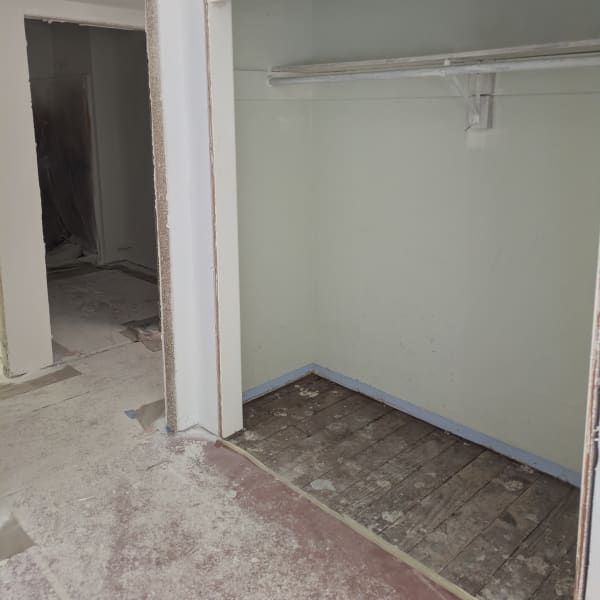 Empty closet and adjacent hallway with unfinished floor and light green walls